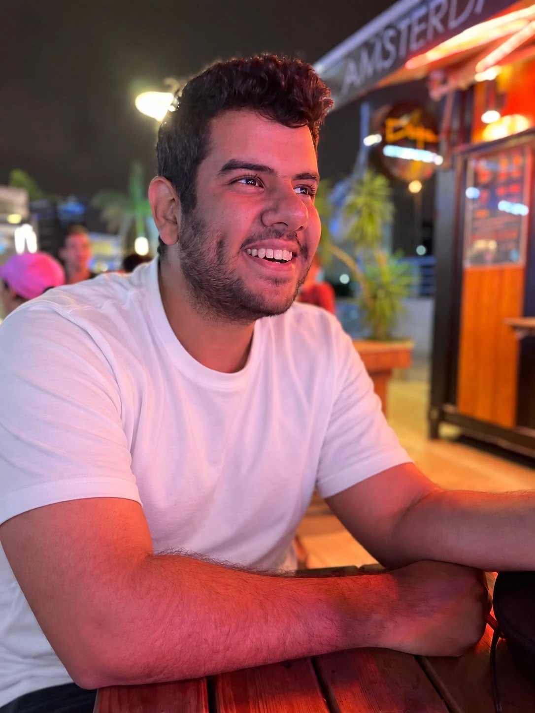 Amir Mohsen smiling, seated at an outdoor table at night